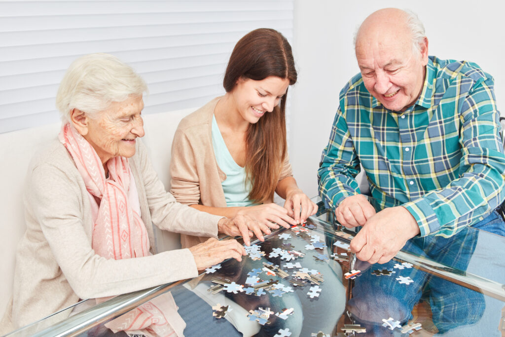 senior,couple,playing,jigsaw,puzzle,against,dementia,with,young,woman
